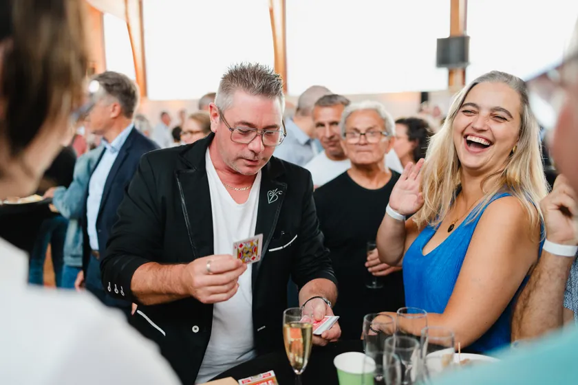 Une invitée éclate de rire pendant un tour de close-up, au milieu d’un cocktail