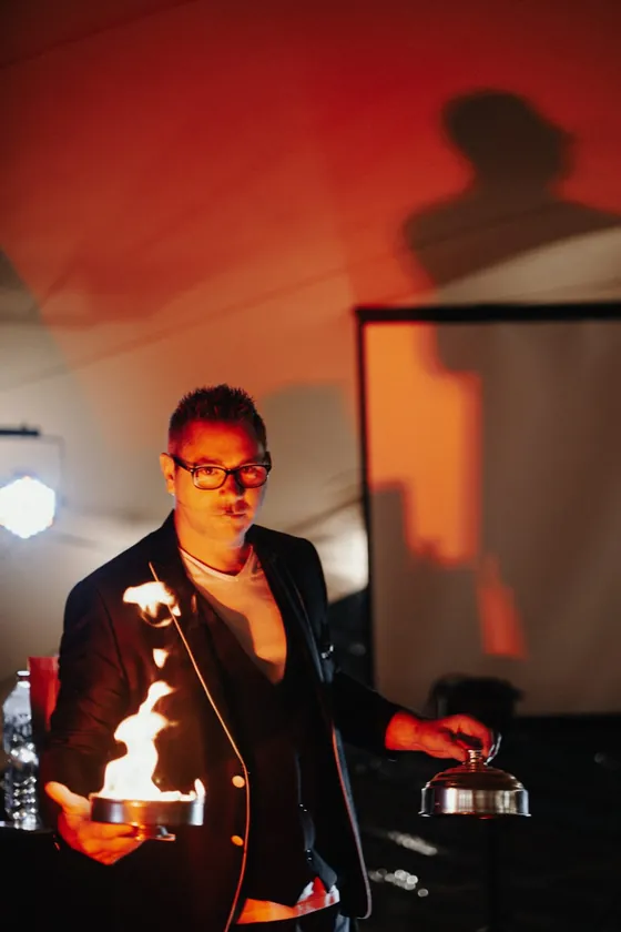 Une flamme dans la main de Vince projette son ombre en grand sur le mur derrière lui