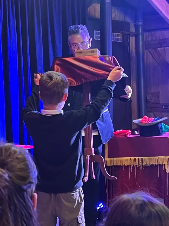 Un enfant appelé sur scène déploie un grand foulard rouge devant Vince