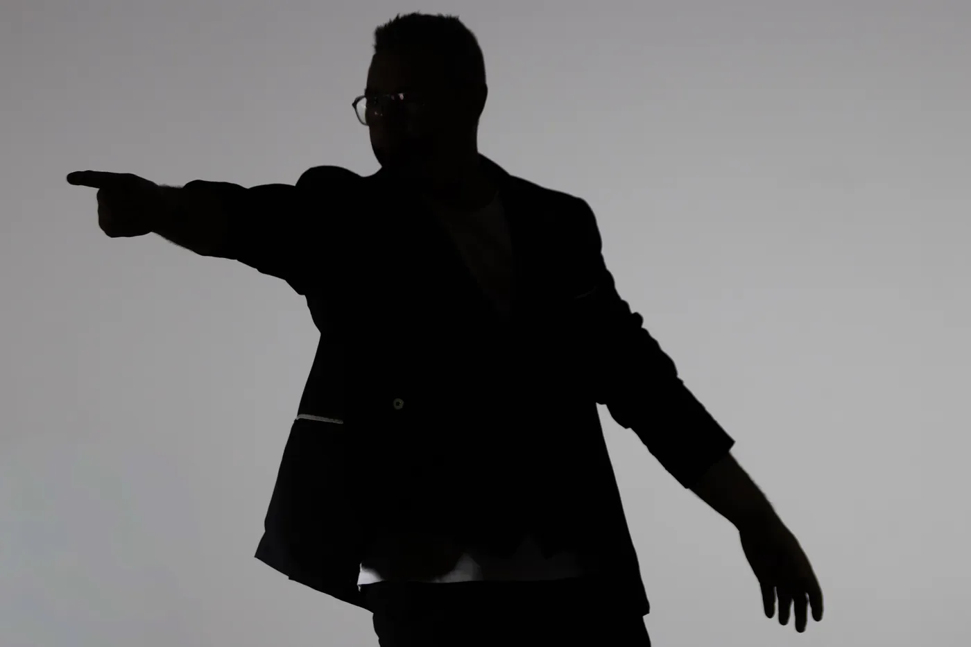 Vince en contre-jour, réduit à sa silhouette, le bras tendu vers le côté